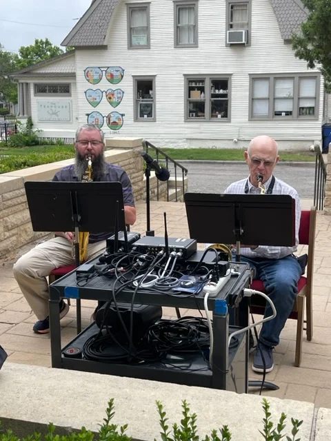 Two musicians playing woodwind instruments outdoors